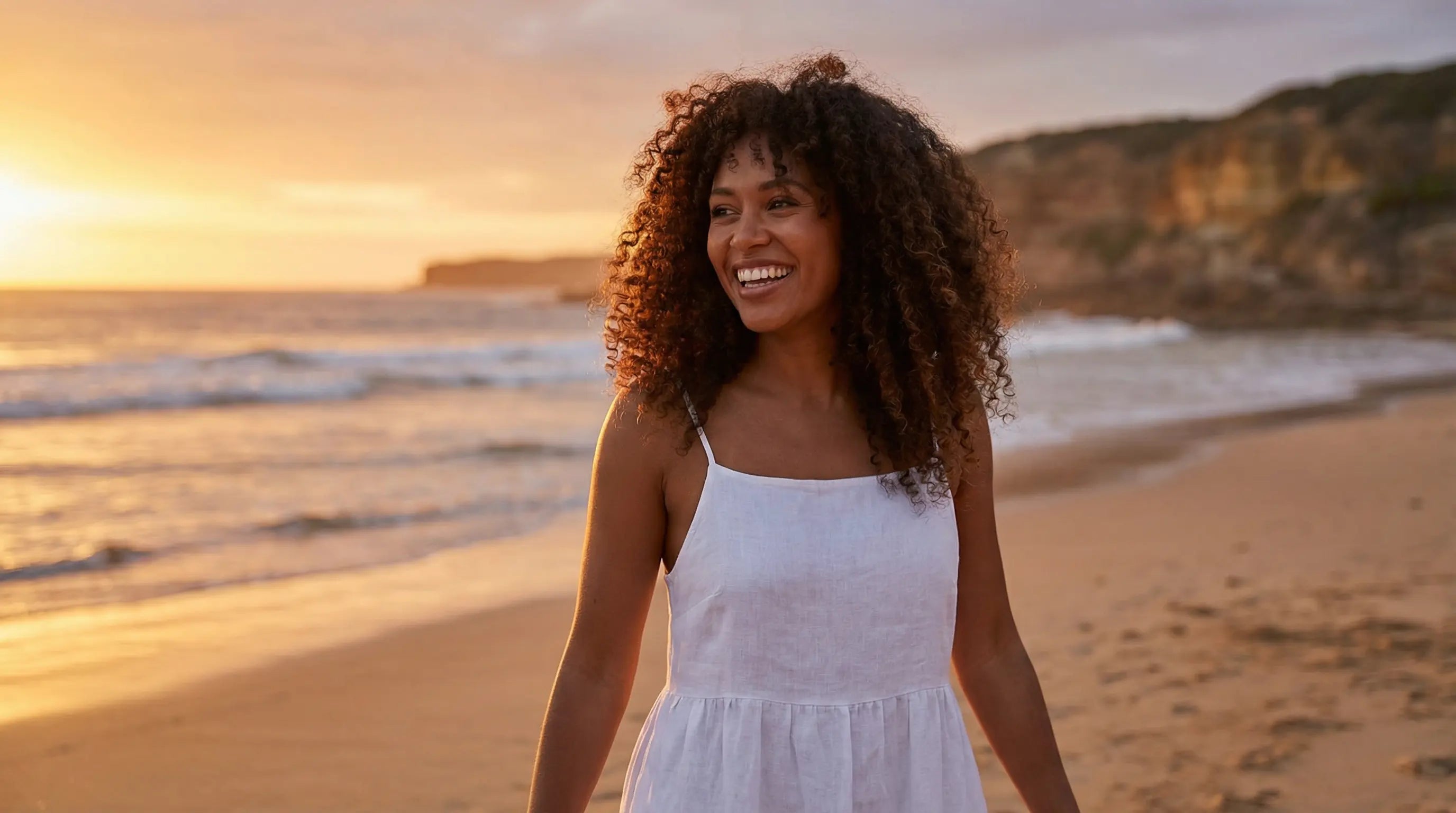 A woman with beautiful, defined curly hair on a sunny Australian beach