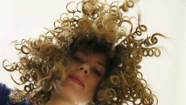 woman with freshly detangled curly hair looking down at camera